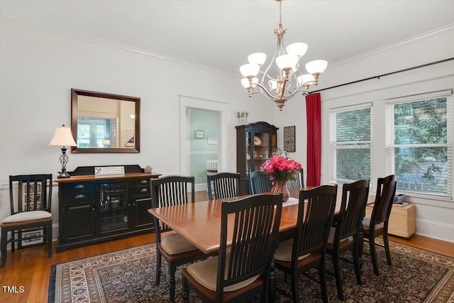 dining room with baseboards, ornamental molding, wood finished floors, and a chandelier