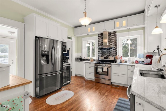 kitchen with wall chimney range hood, appliances with stainless steel finishes, a sink, beverage cooler, and decorative backsplash