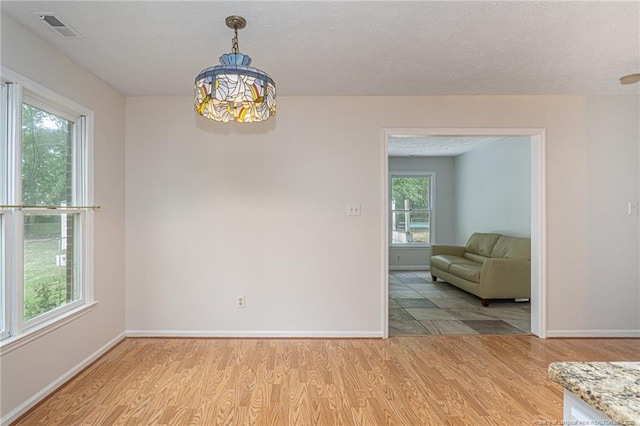 dining area with visible vents, a textured ceiling, baseboards, and light wood-type flooring