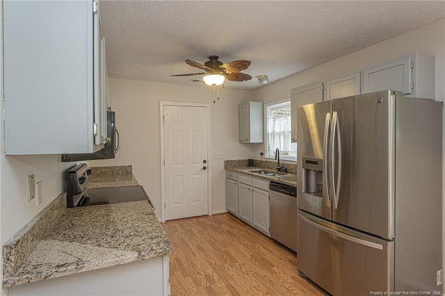 kitchen featuring a sink, light wood finished floors, a textured ceiling, stainless steel appliances, and a ceiling fan