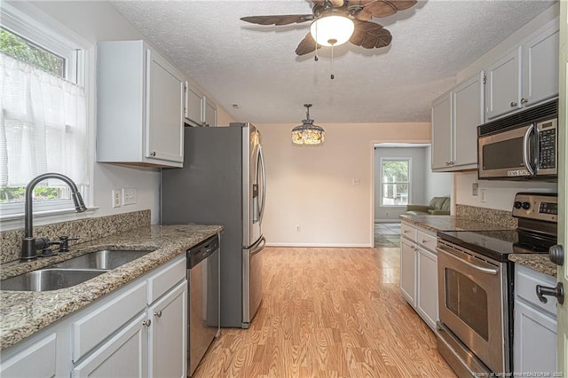 kitchen with a textured ceiling, ceiling fan, appliances with stainless steel finishes, and a sink