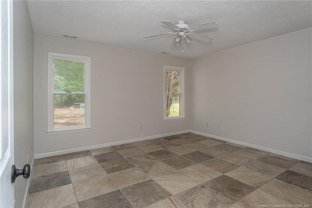 spare room featuring a textured ceiling, ceiling fan, visible vents, and baseboards