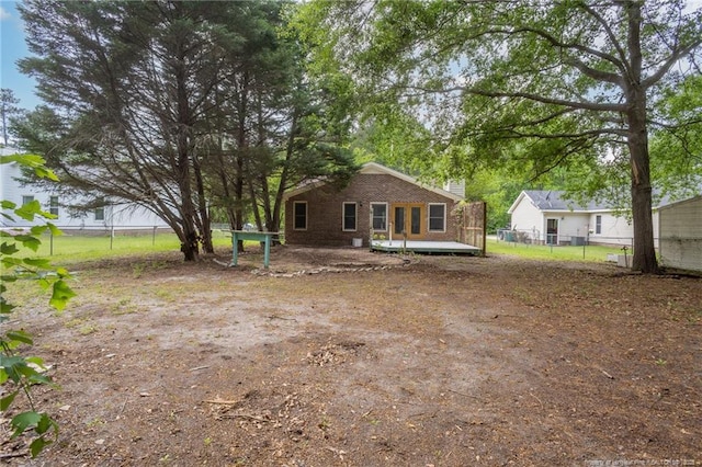 rear view of property featuring brick siding, fence, and a deck