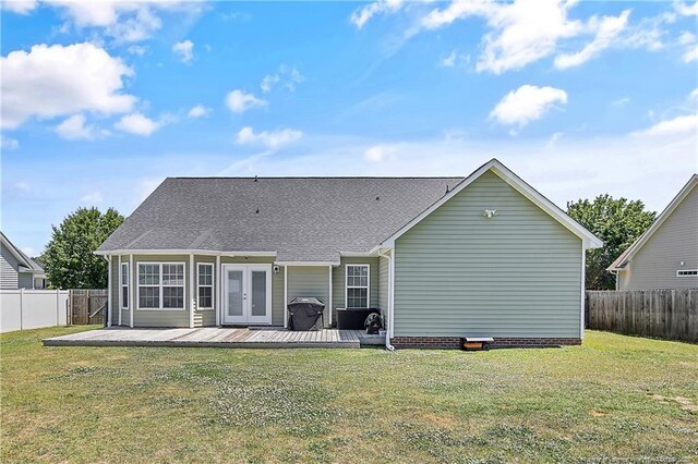 rear view of house featuring french doors, a lawn, a wooden deck, and a fenced backyard