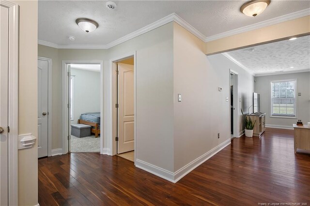 corridor with baseboards, ornamental molding, dark wood-style flooring, and a textured ceiling