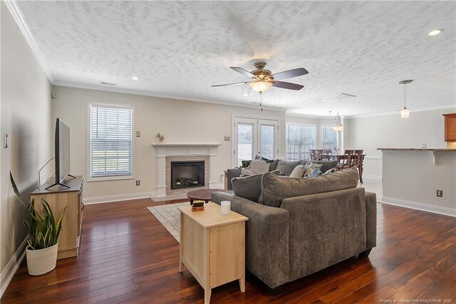 living area featuring a ceiling fan, baseboards, ornamental molding, and dark wood-type flooring