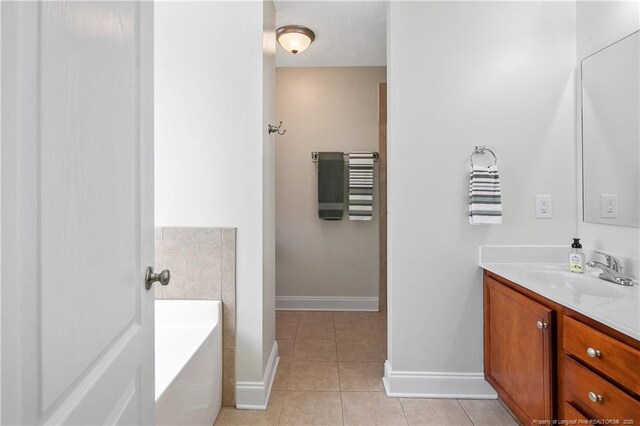 full bath featuring baseboards, tile patterned flooring, vanity, and a bath
