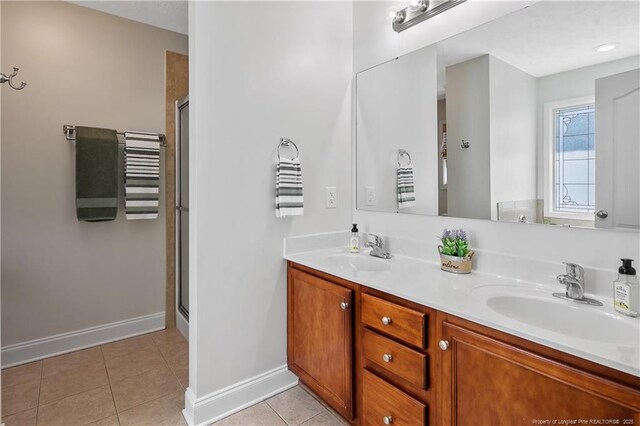 bathroom with baseboards, a sink, tile patterned flooring, and double vanity