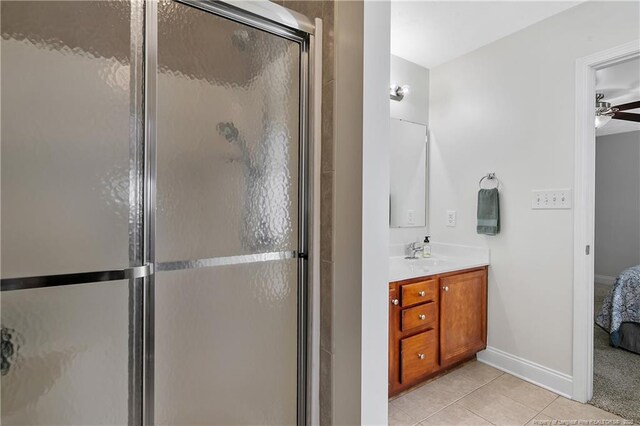 full bathroom featuring a stall shower, vanity, tile patterned floors, baseboards, and ensuite bathroom