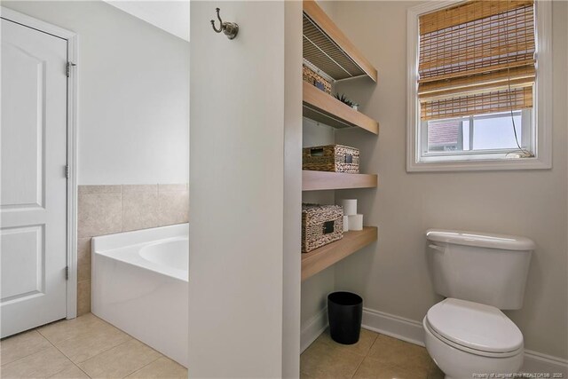 bathroom with a garden tub, baseboards, tile patterned floors, and toilet