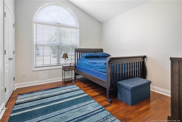 bedroom with baseboards, wood finished floors, and lofted ceiling