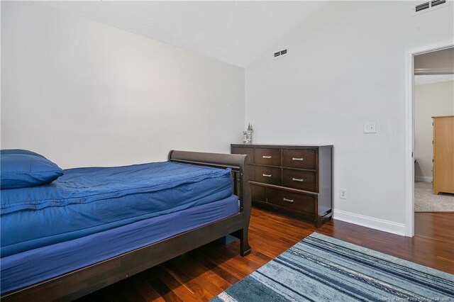 bedroom featuring baseboards, vaulted ceiling, wood finished floors, and visible vents