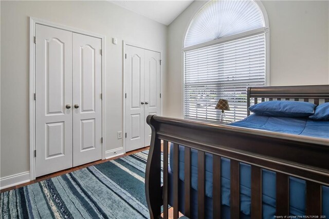 bedroom featuring multiple closets, baseboards, and wood finished floors