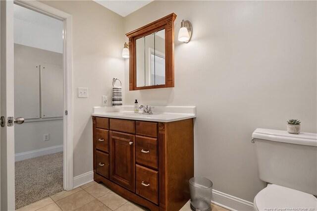 half bathroom featuring tile patterned flooring, baseboards, toilet, and vanity