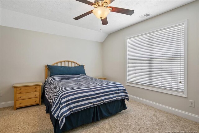 carpeted bedroom featuring a ceiling fan, baseboards, visible vents, and lofted ceiling