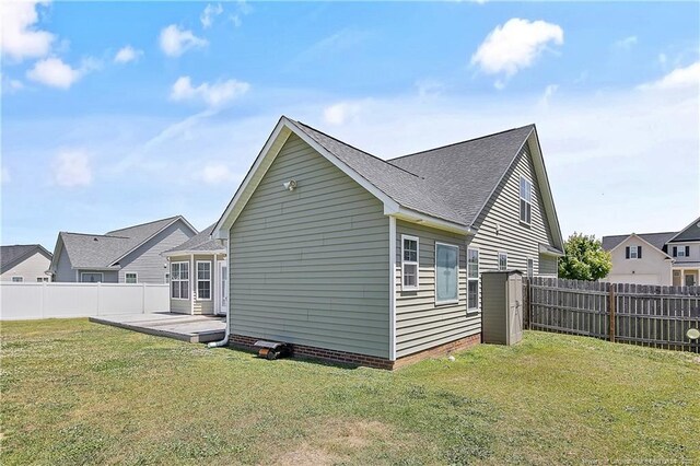 view of side of home with a lawn, a fenced backyard, and roof with shingles