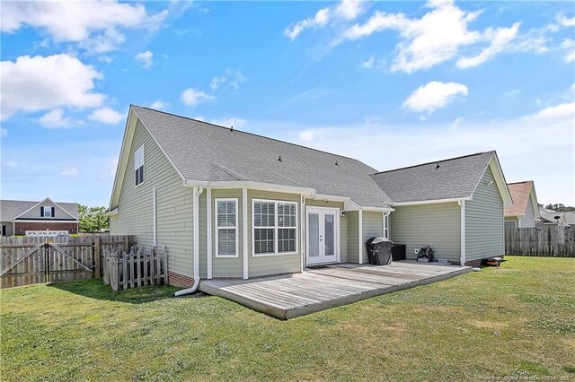 rear view of property with a fenced backyard, a wooden deck, a yard, and french doors
