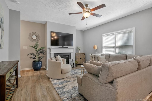 4631 Cedar Pass Dr, Hope Mills, NC 28348 - living room with ceiling fan, a textured ceiling, wood finished floors, baseboards, and a glass covered fireplace