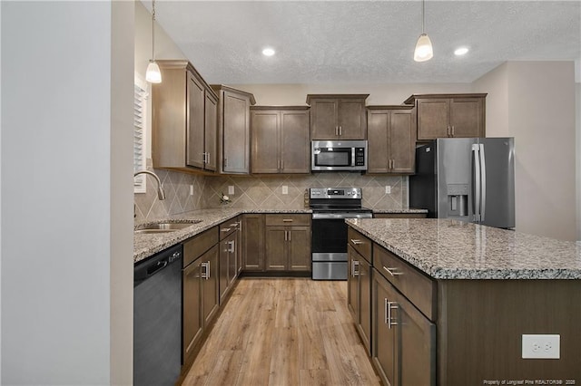 4631 Cedar Pass Dr, Hope Mills, NC 28348 - kitchen with stainless steel appliances, hanging light fixtures, a sink, and light wood-style flooring