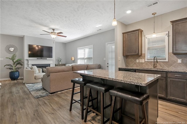 4631 Cedar Pass Dr, Hope Mills, NC 28348 - kitchen with a ceiling fan, a kitchen island, light wood-type flooring, a sink, and a breakfast bar