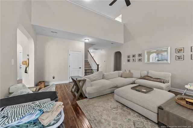living area with a towering ceiling, wood finished floors, stairway, arched walkways, and a ceiling fan