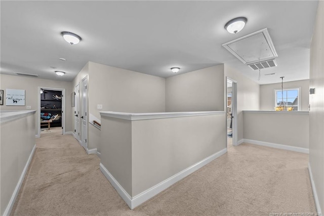 corridor with visible vents, baseboards, attic access, light colored carpet, and an upstairs landing