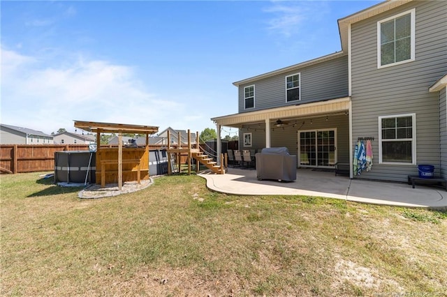 rear view of property with a lawn, ceiling fan, a fenced backyard, and a patio area