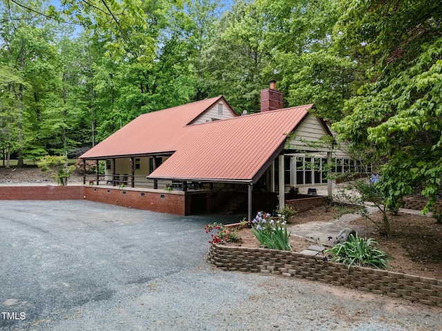 chalet / cabin featuring a standing seam roof, a chimney, and metal roof