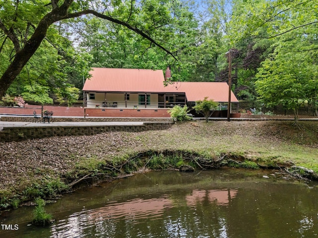 rear view of property with metal roof and a chimney