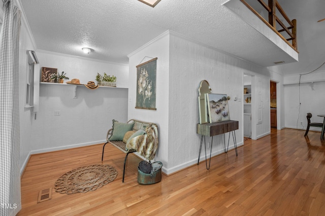 living area with visible vents, ornamental molding, and wood finished floors