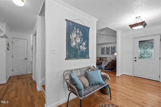 foyer entrance with crown molding, a textured ceiling, and wood finished floors