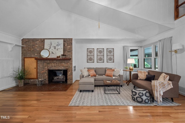 living area featuring a brick fireplace, high vaulted ceiling, and wood finished floors