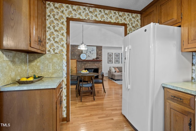 kitchen with brown cabinetry, white refrigerator with ice dispenser, light wood-type flooring, light countertops, and ornamental molding