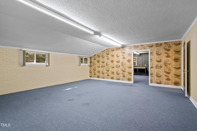 basement with a textured ceiling, carpet floors, and brick wall