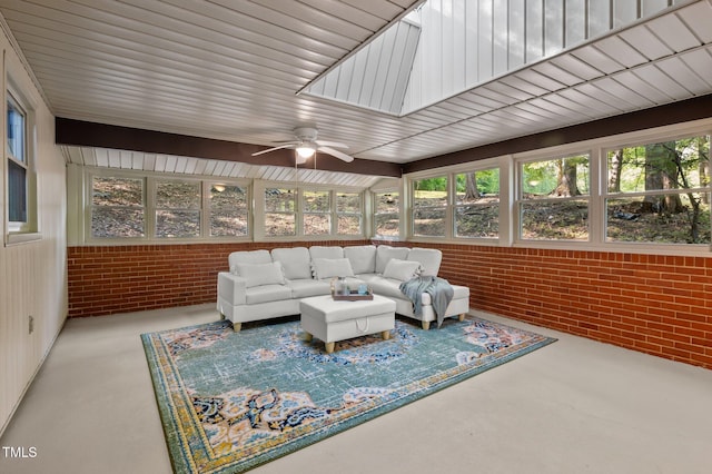 sunroom / solarium featuring concrete flooring, brick wall, and a wealth of natural light
