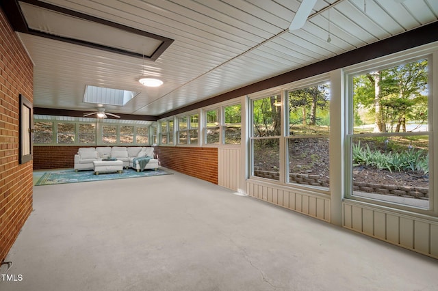 unfurnished sunroom with a ceiling fan, a skylight, and an outdoor hangout area