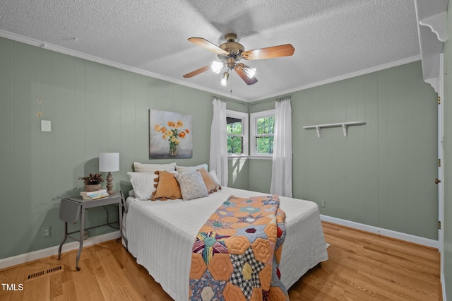 bedroom featuring a textured ceiling, ornamental molding, wood finished floors, and visible vents