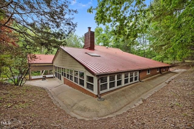 rear view of property with a patio, a chimney, and metal roof