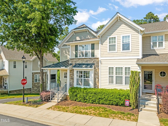 multi unit property featuring a porch, a shingled roof, and stone siding