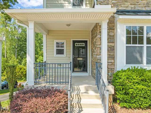 view of exterior entry with a porch and stone siding