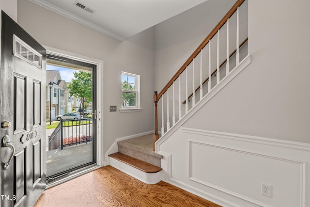 interior space with baseboards, wood finished floors, visible vents, ornamental molding, and stairway