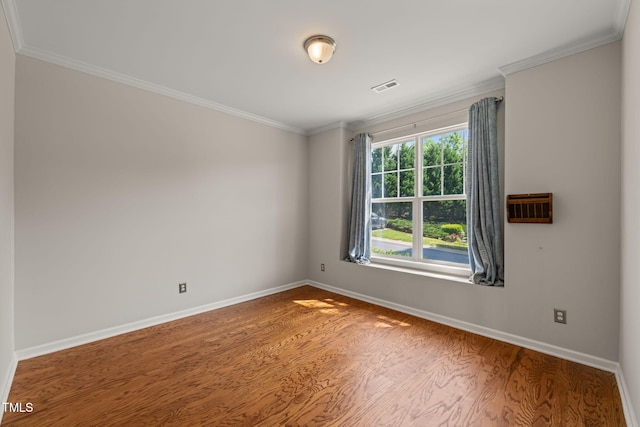 spare room featuring baseboards, crown molding, wood finished floors, and visible vents