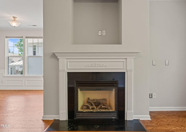 room details featuring visible vents, a fireplace with flush hearth, wood finished floors, and ornamental molding