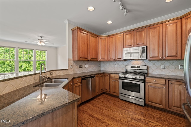 kitchen with a sink, appliances with stainless steel finishes, brown cabinetry, and a ceiling fan