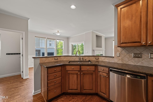 kitchen with brown cabinetry, dishwasher, a sink, a peninsula, and dark wood-style floors