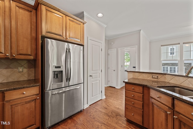 kitchen with crown molding, brown cabinetry, a sink, and stainless steel fridge with ice dispenser