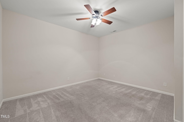 carpeted spare room with baseboards, visible vents, and ceiling fan