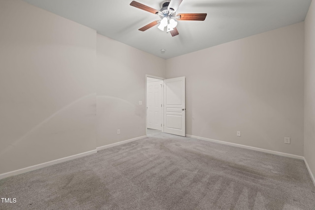 carpeted spare room featuring baseboards and a ceiling fan