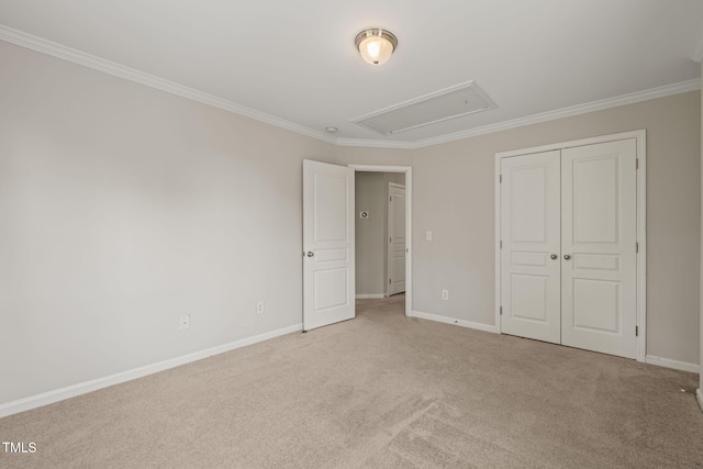 unfurnished bedroom with carpet floors, attic access, baseboards, ornamental molding, and a closet