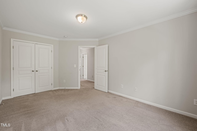 unfurnished bedroom featuring a closet, baseboards, ornamental molding, and carpet flooring
